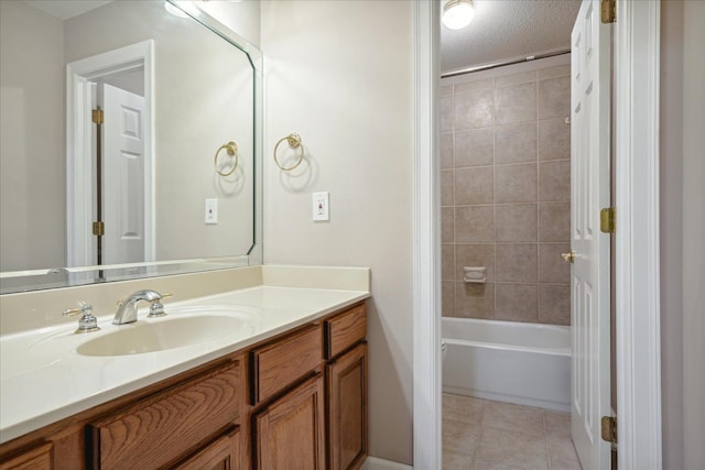 bathroom featuring tile patterned floors, vanity, a textured ceiling, and tiled shower / bath