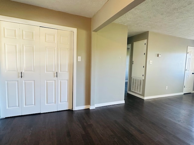 interior space with a textured ceiling and dark hardwood / wood-style flooring