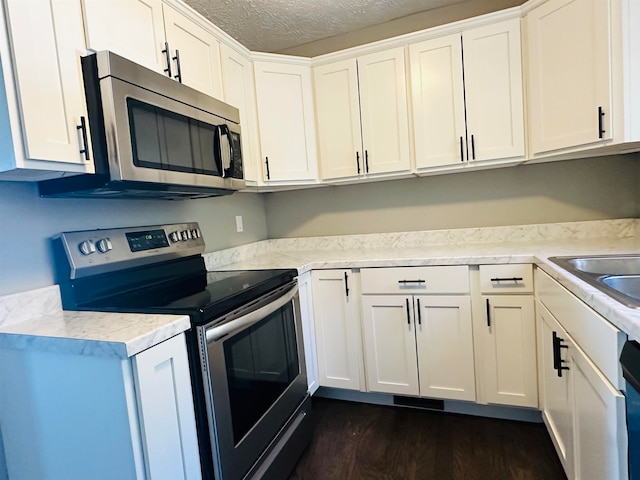 kitchen featuring a textured ceiling, stainless steel appliances, sink, white cabinets, and dark hardwood / wood-style floors