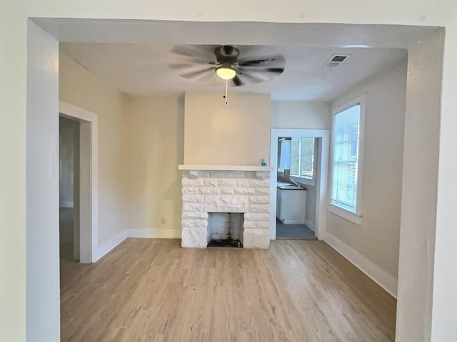 unfurnished living room featuring a fireplace, light hardwood / wood-style flooring, and ceiling fan