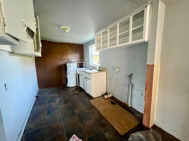 kitchen with sink, electric water heater, and white cabinets