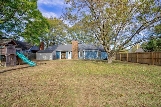 back of house with a playground and a yard