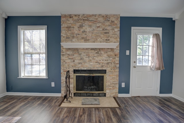 unfurnished living room featuring a large fireplace, dark hardwood / wood-style floors, a healthy amount of sunlight, and crown molding