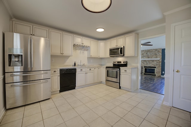 kitchen with crown molding, ceiling fan, light tile patterned floors, a fireplace, and appliances with stainless steel finishes