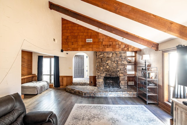 living room with high vaulted ceiling, a stone fireplace, wooden walls, beamed ceiling, and dark hardwood / wood-style flooring