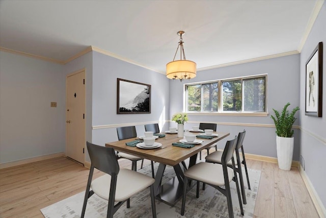 dining space featuring light hardwood / wood-style flooring, ornamental molding, and a notable chandelier