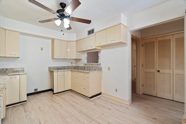 kitchen featuring cream cabinetry, ceiling fan, light stone counters, and light wood-type flooring