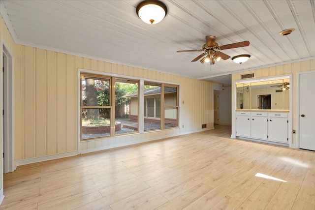 unfurnished living room with ceiling fan, light wood-type flooring, and ornamental molding