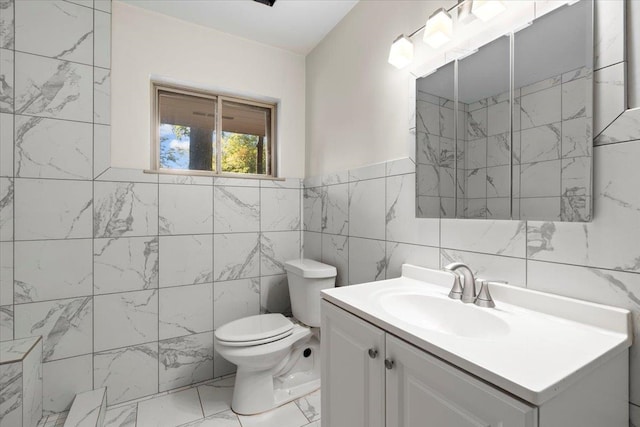 bathroom featuring vanity, toilet, and tile walls