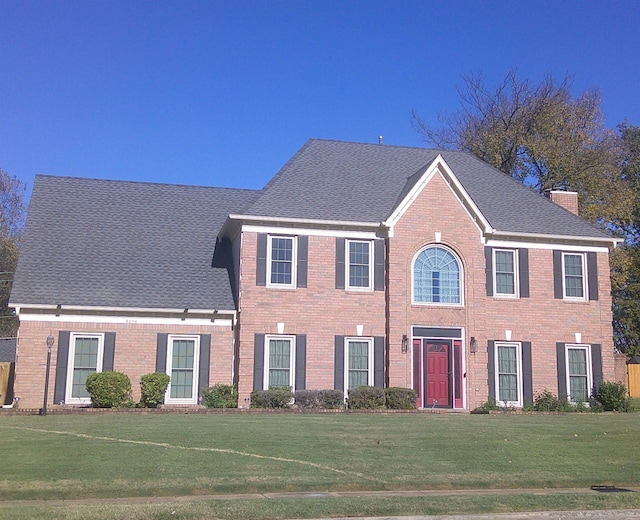 colonial-style house featuring a front yard