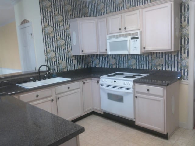 kitchen featuring white cabinets, white appliances, kitchen peninsula, and sink