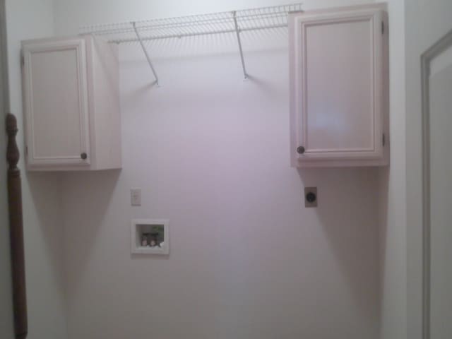 washroom with hookup for an electric dryer, hookup for a washing machine, and cabinets