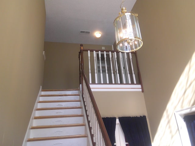 staircase featuring a chandelier and a textured ceiling