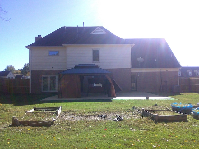 rear view of house featuring a gazebo, a lawn, and a patio