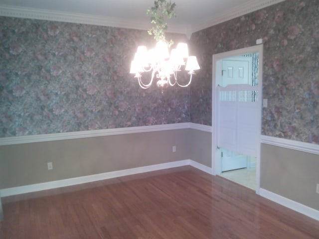 unfurnished dining area with ornamental molding, a notable chandelier, and hardwood / wood-style flooring