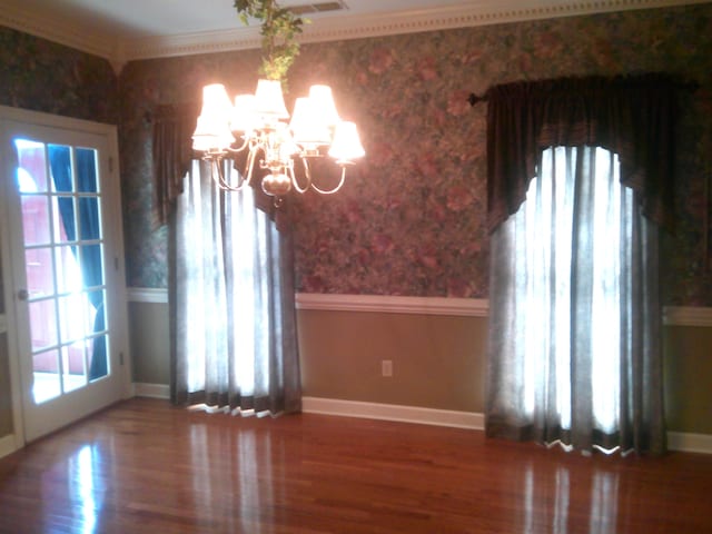 interior space featuring wood-type flooring, an inviting chandelier, and ornamental molding