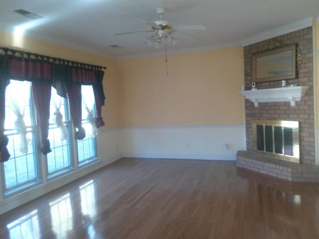 unfurnished living room with ceiling fan, crown molding, wood-type flooring, and a fireplace