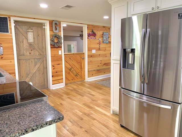 kitchen with wood walls, white cabinetry, stainless steel refrigerator with ice dispenser, and light hardwood / wood-style flooring