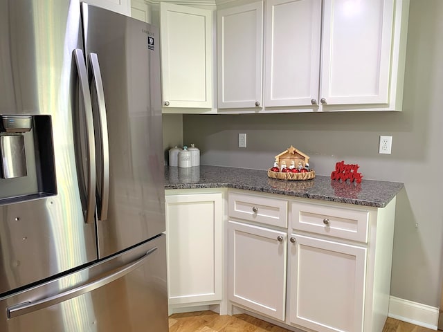 kitchen featuring white cabinetry, light hardwood / wood-style flooring, dark stone counters, and stainless steel refrigerator with ice dispenser