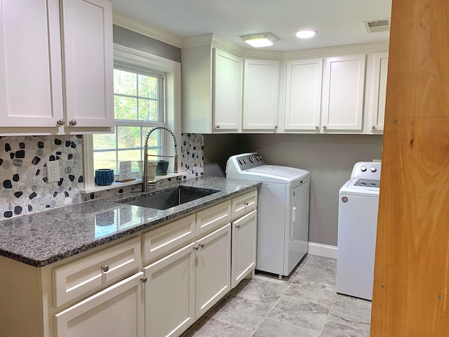 clothes washing area featuring separate washer and dryer, sink, and cabinets