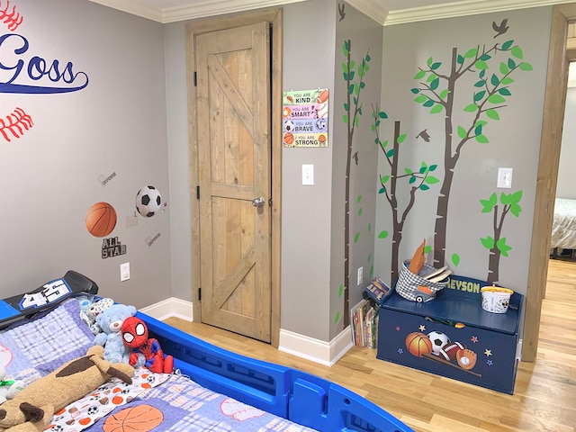 bedroom featuring wood-type flooring, a barn door, and crown molding