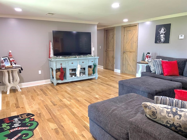 living room featuring a barn door, light hardwood / wood-style flooring, and ornamental molding