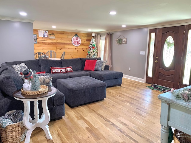 living room with light hardwood / wood-style floors, ornamental molding, and wood walls