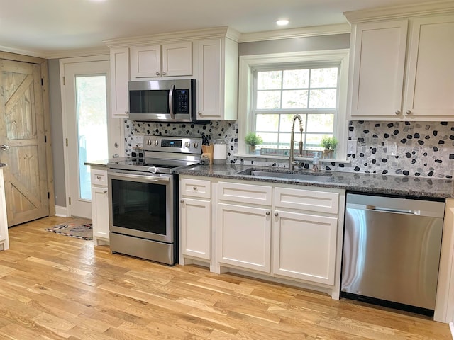 kitchen with backsplash, sink, light hardwood / wood-style flooring, ornamental molding, and stainless steel appliances