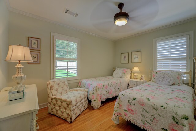 bedroom with light wood-type flooring, ceiling fan, and crown molding