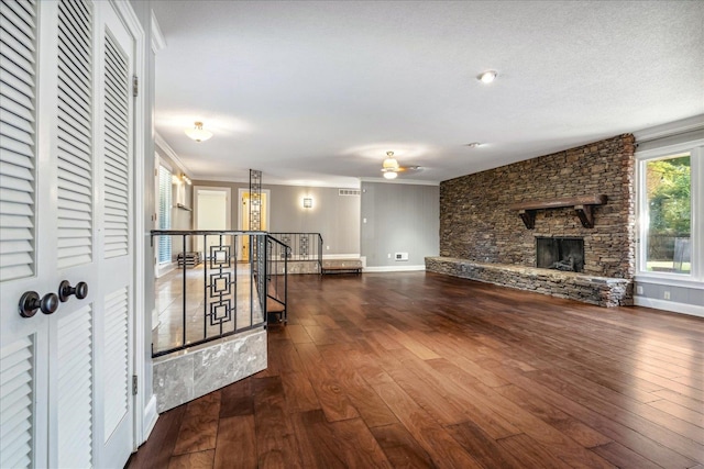 living room with a stone fireplace, crown molding, dark hardwood / wood-style flooring, and ceiling fan