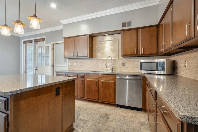 kitchen featuring sink, stainless steel appliances, pendant lighting, a kitchen island, and ornamental molding