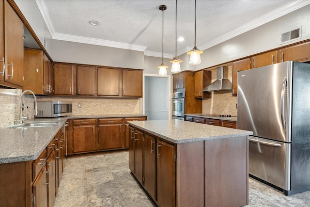 kitchen featuring wall chimney exhaust hood, appliances with stainless steel finishes, decorative light fixtures, a kitchen island, and ornamental molding