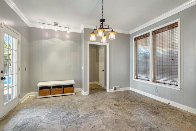 unfurnished room featuring track lighting, wood walls, ornamental molding, and a chandelier