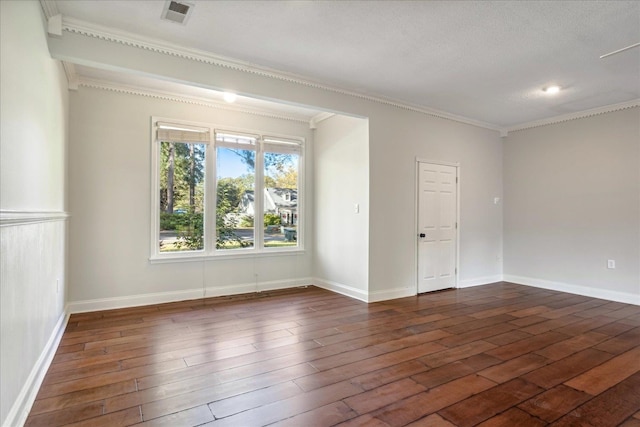 spare room with a textured ceiling, crown molding, and dark wood-type flooring