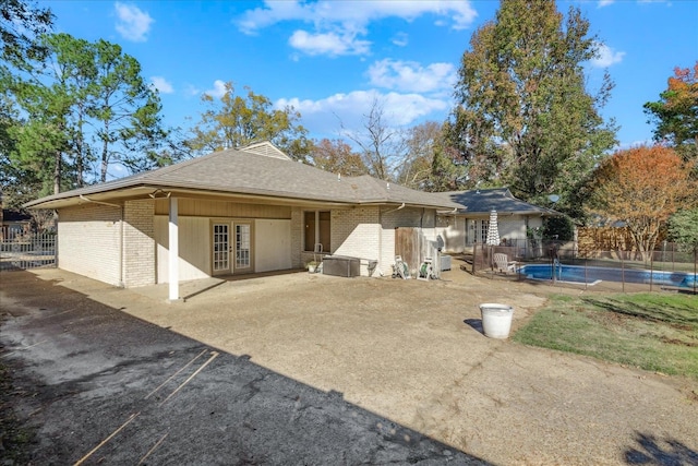 back of property featuring a fenced in pool, french doors, and a patio