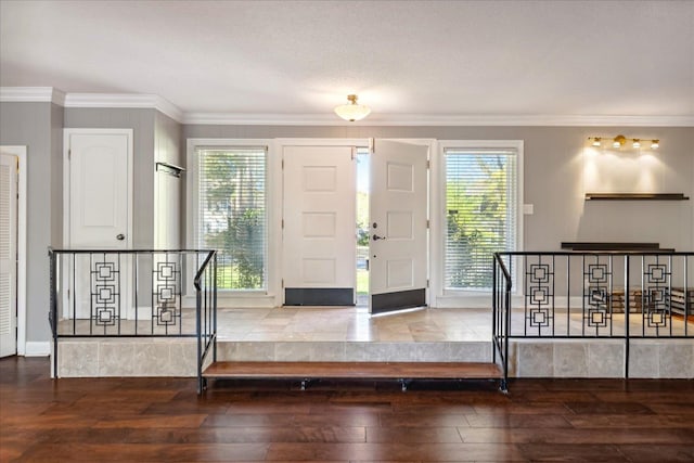 foyer featuring wood-type flooring, ornamental molding, and a healthy amount of sunlight