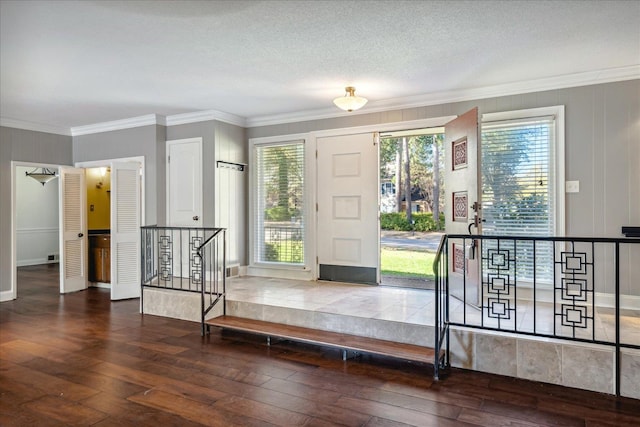 foyer with ornamental molding, a textured ceiling, and dark wood-type flooring