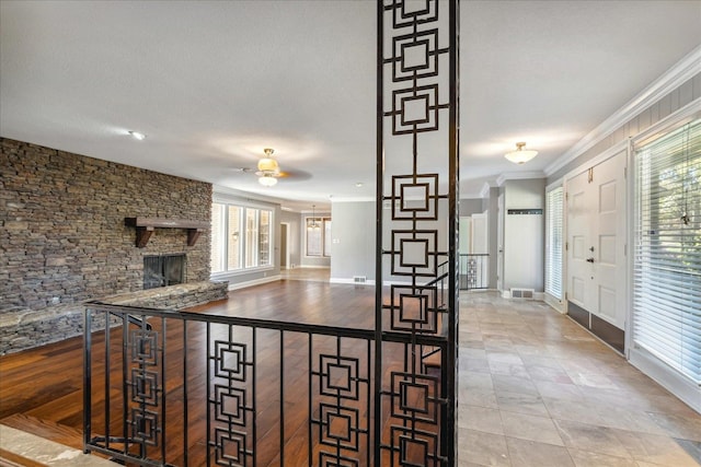 kitchen featuring a textured ceiling, a stone fireplace, ceiling fan, and ornamental molding