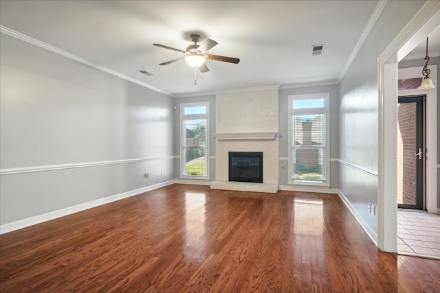 unfurnished living room with hardwood / wood-style flooring, a brick fireplace, ceiling fan, and ornamental molding