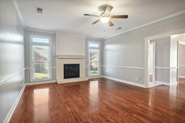 unfurnished living room with a fireplace, crown molding, dark wood-type flooring, and a healthy amount of sunlight