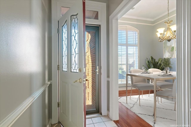 foyer entrance with an inviting chandelier, light hardwood / wood-style flooring, and ornamental molding