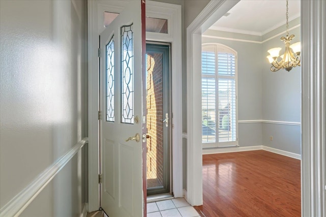 foyer featuring ornamental molding, light hardwood / wood-style floors, and a notable chandelier