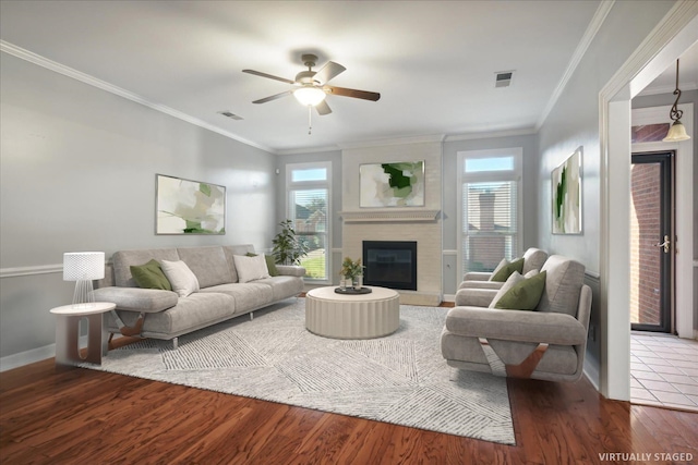 living room featuring a large fireplace, crown molding, plenty of natural light, and wood-type flooring