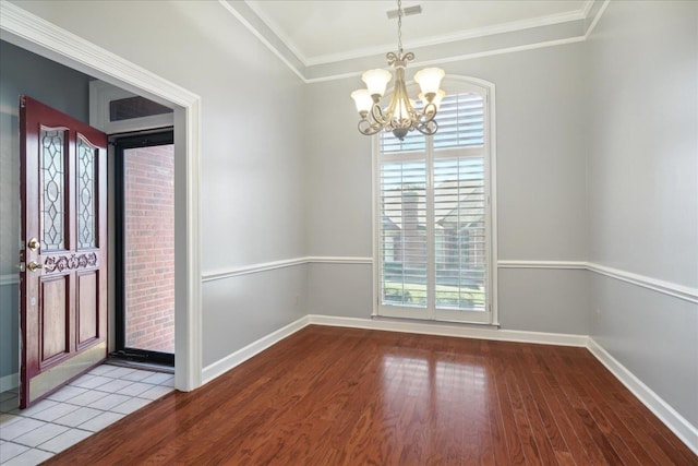 spare room with a notable chandelier, light wood-type flooring, and crown molding