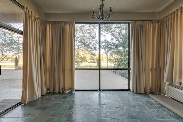 unfurnished dining area with a chandelier and a textured ceiling