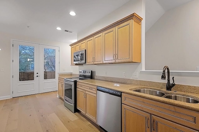 kitchen with lofted ceiling, french doors, sink, light hardwood / wood-style flooring, and appliances with stainless steel finishes