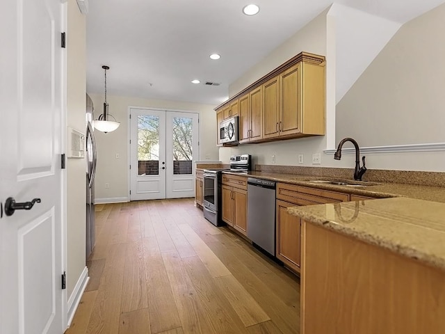 kitchen featuring appliances with stainless steel finishes, light wood-type flooring, french doors, sink, and pendant lighting