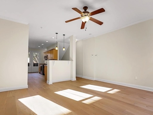 unfurnished living room featuring ceiling fan, light wood-type flooring, ornamental molding, and french doors