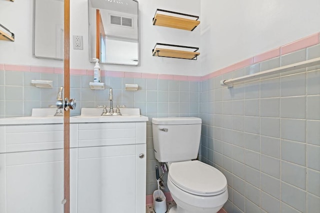 bathroom with vanity, toilet, and tile walls