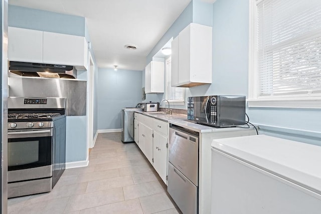 kitchen featuring stainless steel appliances, sink, white cabinets, washer / clothes dryer, and range hood